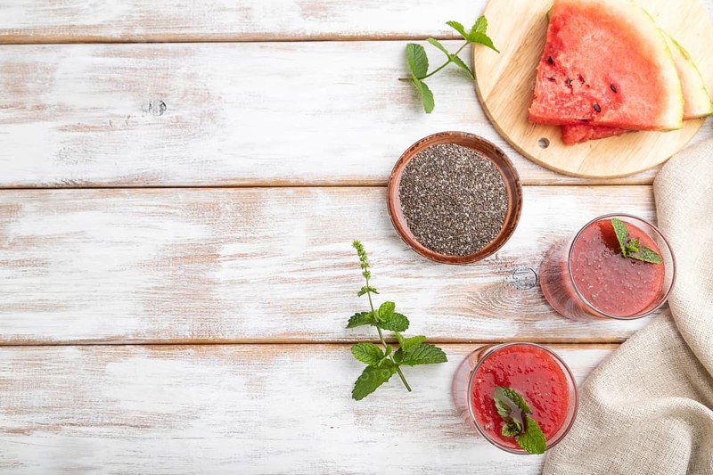 Watermelon juice with chia seeds and mint in glass on a white wooden background with linen textile. Healthy drink concept. Top view, copy space, flat lay