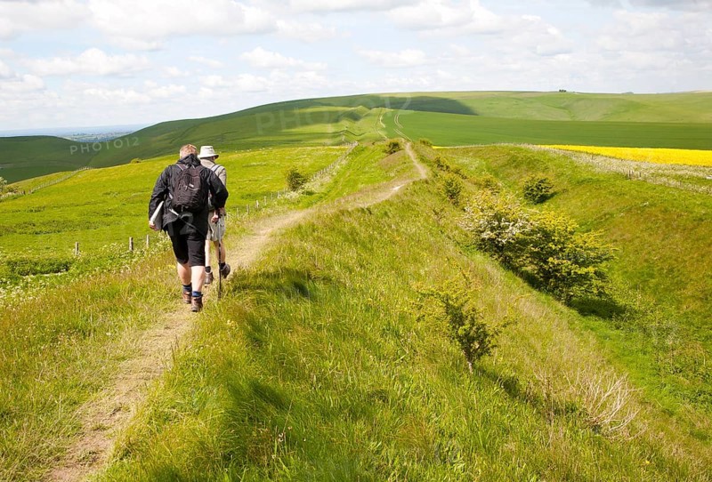 Two men walking along the ditch and embankment of the Wansdyke a Saxon defensive structure on All Cannings chalk downs near Tan Hill, Wiltshire, England, United Kingdom, Europe