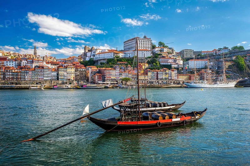 View of Porto city and Douro river with traditional boats with port wine barrels and sailing ship from famous tourist viewpoint Marginal de Gaia riverfront. Porto, Vila Nova de Gaia, Portugal, Europe