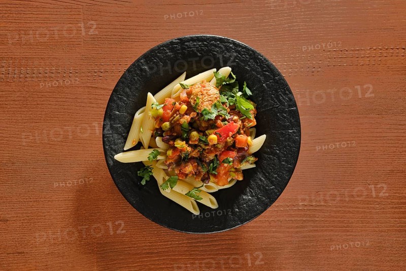 Overhead view of plate with beef slices fried with vegetables and spicy sauce with pasta