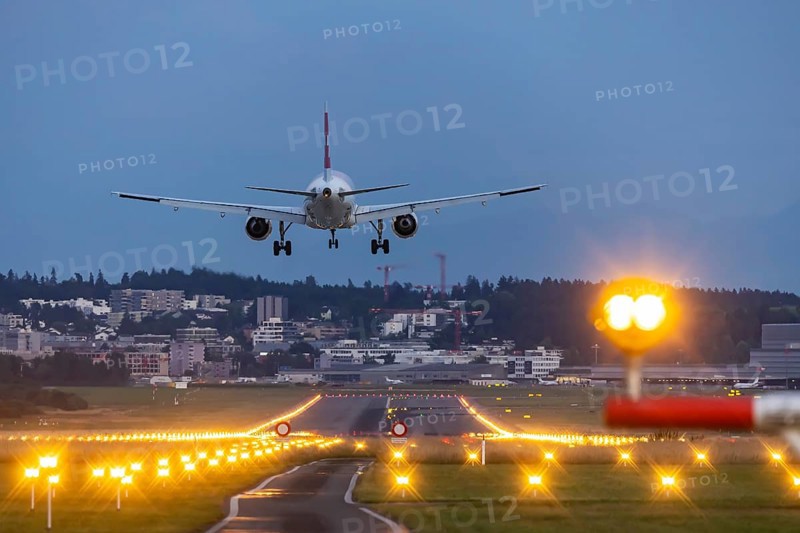 Aircraft of the airline Swiss landing in the evening with illuminated runway. Zurich Airport, Switzerland, Europe