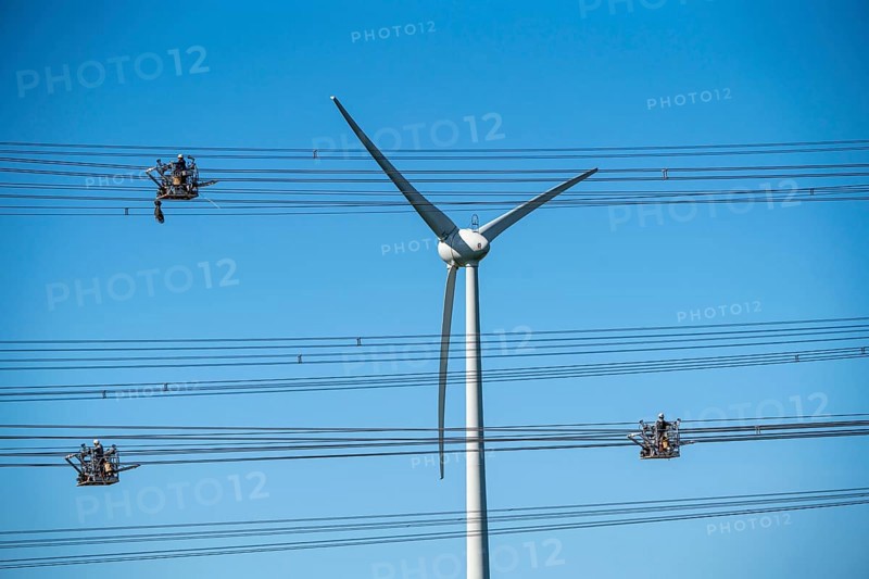 Construction of a new line route, 380 KV extra-high voltage line between Osterath and Gohr, near Neuss, fitters in cable trolleys, on the conductor cables, installing field spacers at great heights, wind power station, North Rhine-Westphalia, Germany, Europe