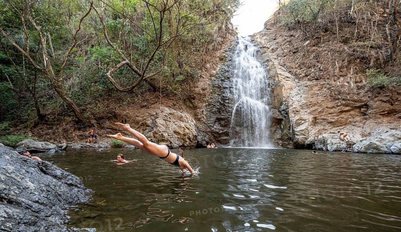 Young woman jumping into the water, Cascada Montezuma waterfall, Montezuma, Nicoya Peninsula, Puntarenas Province, Costa Rica, Central America