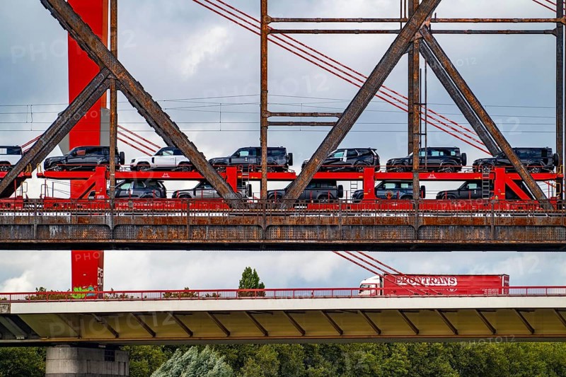 The Beeckerwerther Rhine bridge of the A42 motorway, truck traffic, in front of it the Haus-Knipp railway bridge, goods train, car train, new car of the type, Land Rover Defender, Rhine near Duisburg, North Rhine-Westphalia, Germany, Europe