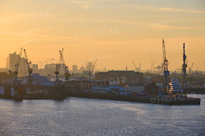 Harbour at sunrise, cranes rise into the sky, in the background buildings, Elbe Philharmonic Hall, and an industrial skyline, Hamburg, Germany, Europe