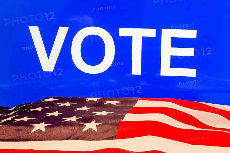 USA flag in front of a blue screen with the inscription VOTE