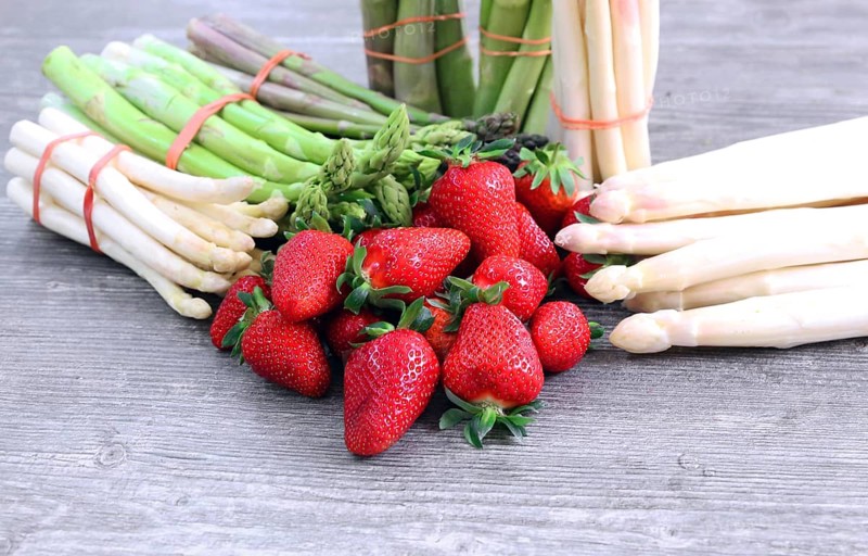 Green asparagus, white asparagus and fresh strawberries decorated on a rustic wooden table