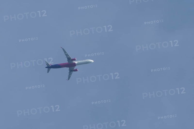 Airbus A320 aircraft of Wizz air airlines in flight across a blue sky, England, United Kingdom, Europe