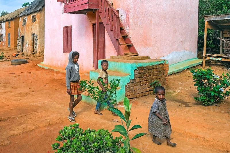 Malagasy children in street of rural village with traditional houses in the Ambositra District, Amoron'i Mania Region, Central Madagascar