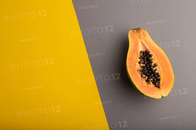 Ripe cut papaya on yellow and gray pastel background. Top view, flat lay, copy space. Tropical, healthy food, women health concept, minimalism