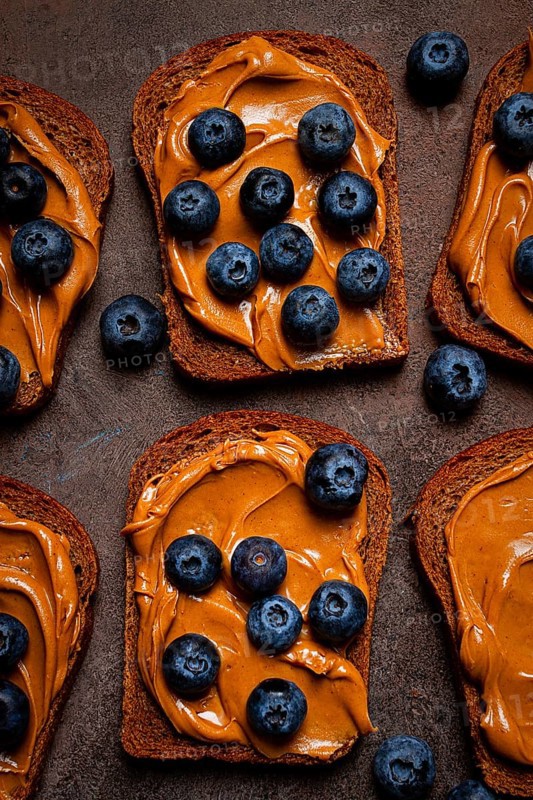 Rye bread with peanut paste and fresh blueberries, top view, no people