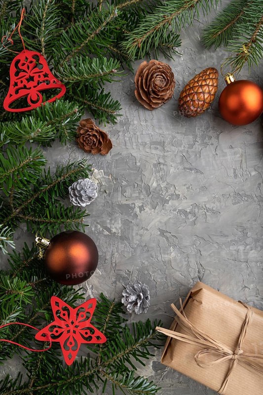 Christmas or New Year composition. Decorations, cones, cinnamon, fir and spruce branches, cup of coffee, wool scarf on a gray concrete background. Top view, copy space, flat lay