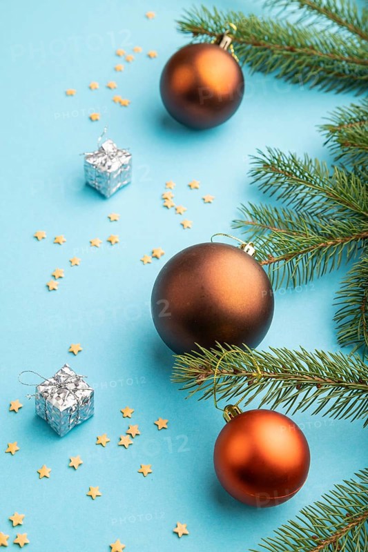 Christmas or New Year composition. Decorations, bronze balls, fir and spruce branches, on a blue paper background. Side view, close up