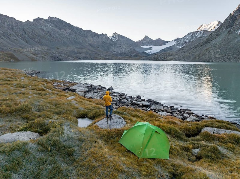 Hikers wild camping, camping with tent in the mountains with glacier, mountain pass and mountain lake Ala-Kul Lake, Tien Shan, Kyrgyzstan, Asia
