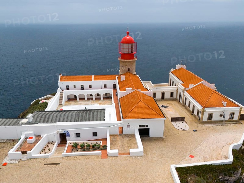 Close-up of a red lighthouse with several white buildings and a courtyard surrounded by the ocean, aerial view, lighthouse, Cabo de São Vicente, Cape St Vincent, Cape St Vincent, Sagres, Portugal, Europe