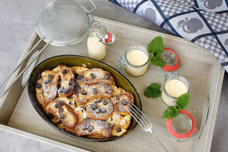 Swabian cuisine, Ofenschlupfer, sweet main course or dessert, dessert, sweet dish, typical Swabian, classic, from the oven, casserole, leftovers, rolls with sultanas, apples, gratinated, vanilla sauce, icing sugar, served on a tray, home cooking, traditional cuisine, food photography, studio, Germany, Europe