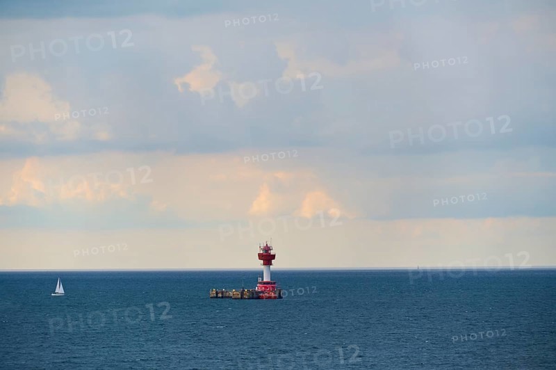 A red lighthouse stands on a calm, blue sea under a slightly cloudy sky, with a small sailing boat in the background, Kiel Lighthouse, pilot station, Kiel, Schleswig-Holstein, North Sea, Germany, Europe