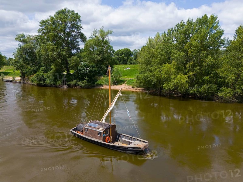 A lonely boat floats on a calm river, surrounded by green landscape and trees under a clear sky, aerial view, Les Bateliers de Saint Chenonceaux, The Boatmen of Saint Chenonceaux, Loire, France, Europe