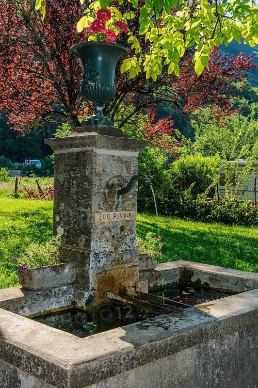 Old historic fountain with curved tap Water spout for permanent drinking water supply Water supply clean drinkable water for human consumption Food below sign Eau potable, above floral arrangement in goblet Goblet, Les Planches-prés-Arbois, Bourgogne-Franche-Comté, Département Jura, France, Europe