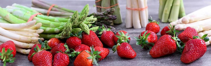 Green asparagus, white asparagus and fresh strawberries decorated on a rustic wooden table