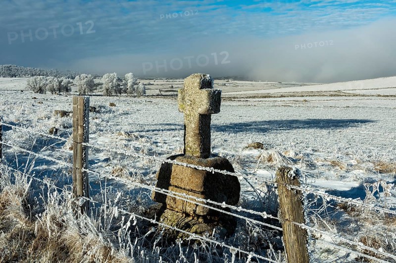 Aubrac plateau in winter. Stone cross at the side of a path. Lozere department. Occitanie. France