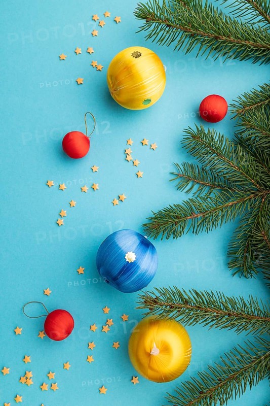 Christmas or New Year composition. Decorations, blue, red, yellow balls, fir and spruce branches, on a blue paper background. Top view, close up, flat lay