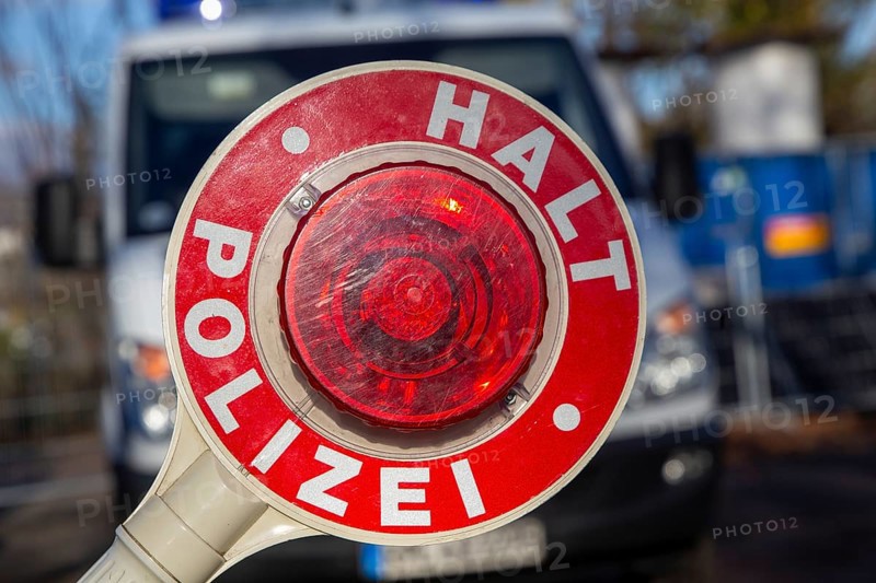 Police check: close-up of a police trowel with the inscription HALT POLIZEI in front of a police car