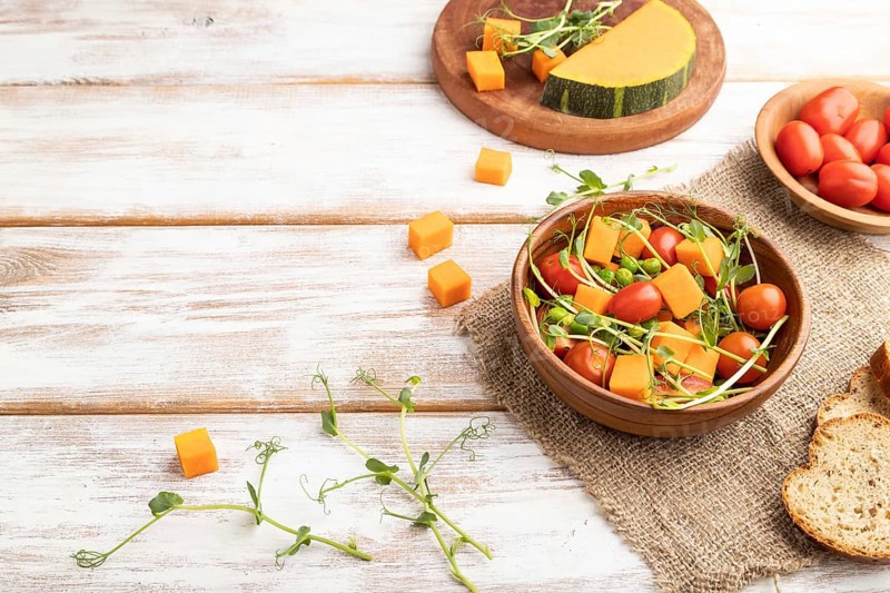 Vegetarian vegetable salad of tomatoes, pumpkin, microgreen pea sprouts on white wooden background and linen textile. Side view, copy space