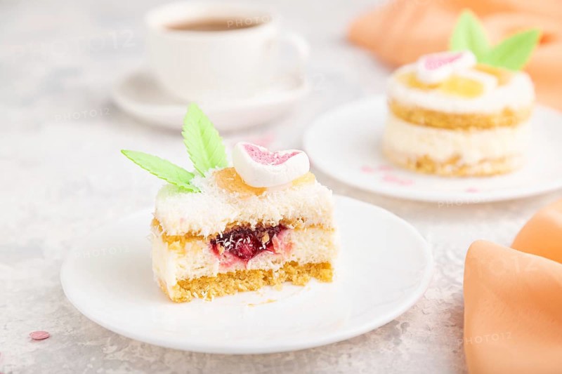 Decorated cake with milk and coconut cream with cup of coffee on a gray concrete background and orange textile. Side view, close up, selective focus