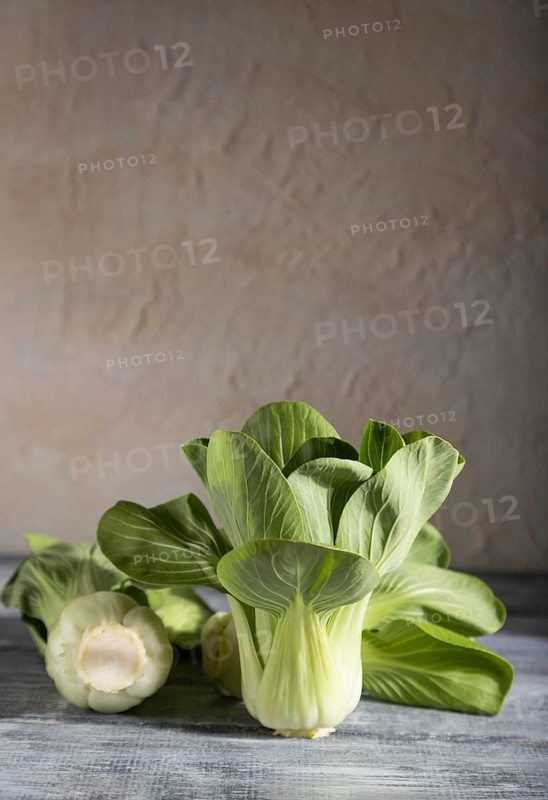 Fresh green bok choy or pac choi chinese cabbage on a gray wooden background. Hard light, contrast. Side view, copy space, selective focus