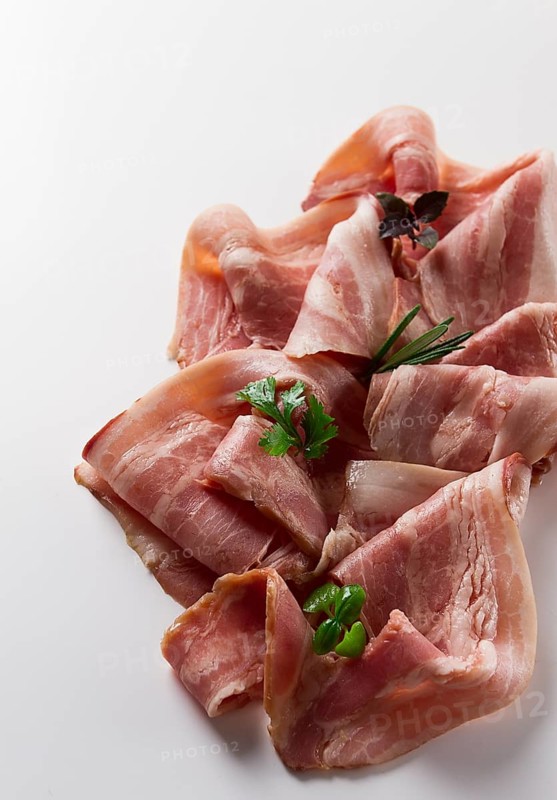 Raw bacon, sliced, with micro greenery and spices, on a white background, close-up