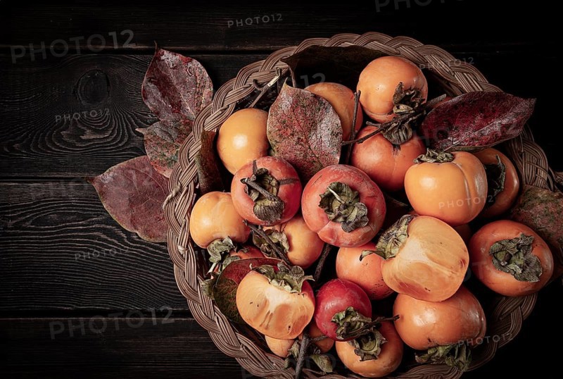 Fresh persimmon in a basket, with leaves, top view, no people