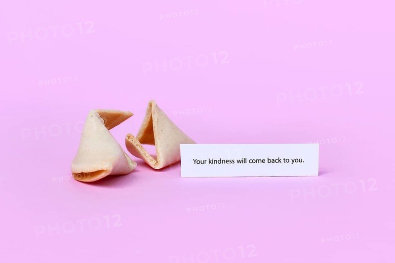 Fortune cookie with motivational text saying 'Your kindness will come back to you on pink background