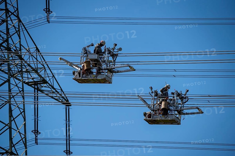 Construction of a new line route, 380 KV extra-high-voltage line between Osterath and Gohr, near Neuss, fitters in line trolleys, on the conductor cables, installing field spacers at great heights, North Rhine-Westphalia, Germany, Europe
