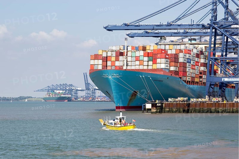 Small foot ferry passenger boat dwarfed by huge Edith Maersk container ship, Port of Felixstowe, Suffolk, England, UK