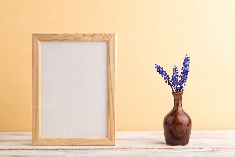 Wooden frame with blue muscari hyacinth flowers in ceramic vase on orange pastel background. side view, copy space, still life, mockup, template, spring, summer minimalism concept
