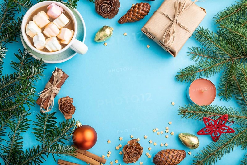 Christmas or New Year frame composition. Decorations, box, cinnamon, cones, fir and spruce branches, cup of coffee, on a blue paper background. Top view, copy space, flat lay