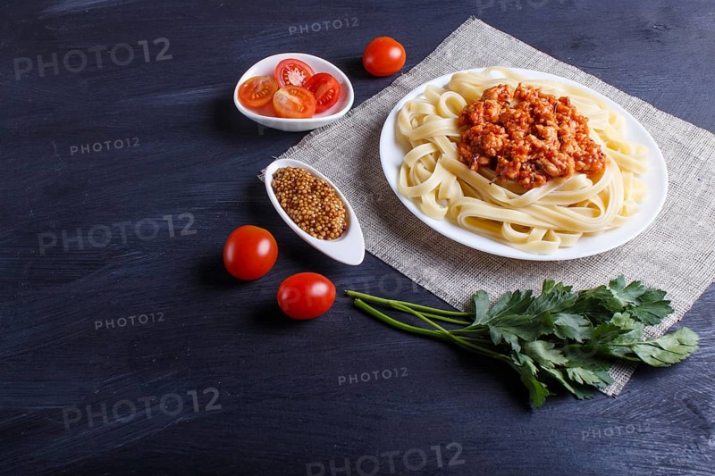 Fettuccine bolognese pasta with minced meat on black wooden background. close up, copy space