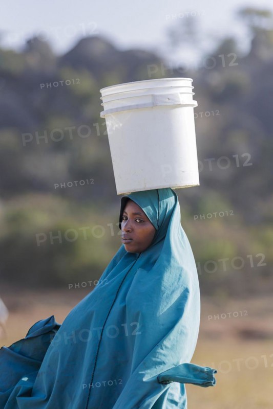 Woman with a bucket of water on her head in Maraban Dare community, Plateau state, 07/02/2024