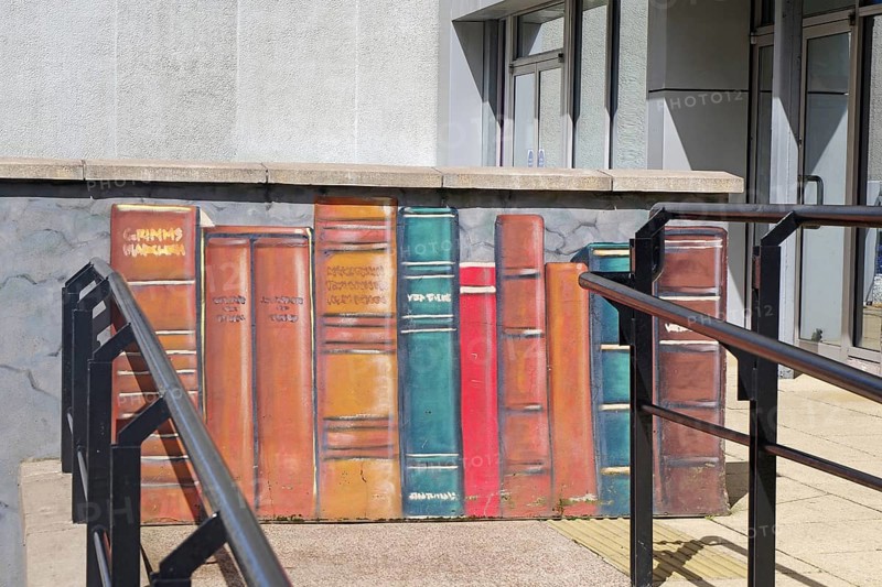 A mural shows colourful books lined up on a wall in the city, Mural Trail, Glasgow, Scotland, United Kingdom, Europe