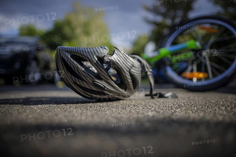 Symbol photo on the subject of bicycle accidents (posed scene) . A broken bicycle helmet lies next to a bicycle on a road Berlin, 21/08/2024