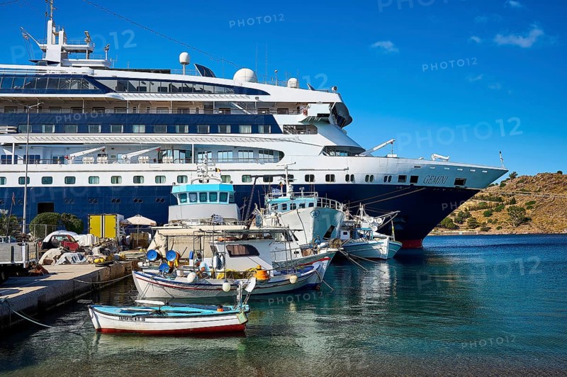 A large cruise ship moored in the harbour of a Greek island, surrounded by smaller fishing boats on blue water, Skala, Patmos, Dodecanese, Greek Islands, Greece, Europe