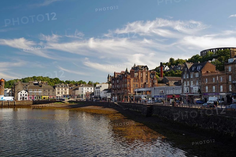 Coastal town with historic buildings along a harbour under a clear sky with some clouds, harbour town, Oban, Mc Craig Tower, Scotland, United Kingdom, Europe