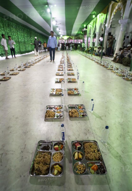 Volunteers distribute and arrange rows of 'iftar' meal for devotees to break their fast, during the holy month of Ramadan, at Burha Jame Masjid, on March 13, 2024 in Guwahati, Assam, India, Asia
