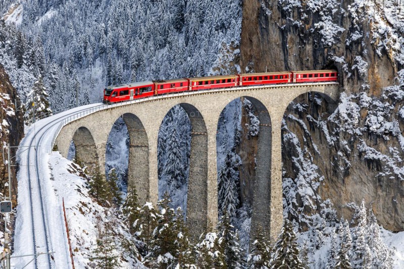 Rhaetian Railway train at the famous Landwasser Viaduct on the Albula railway Stadler Rail passenger train in Filisur, Switzerland, Europe