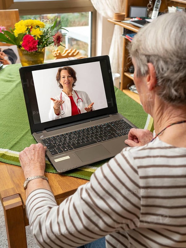 Symbolic image of telemedicine, patient speaking to a doctor in a video conference from home