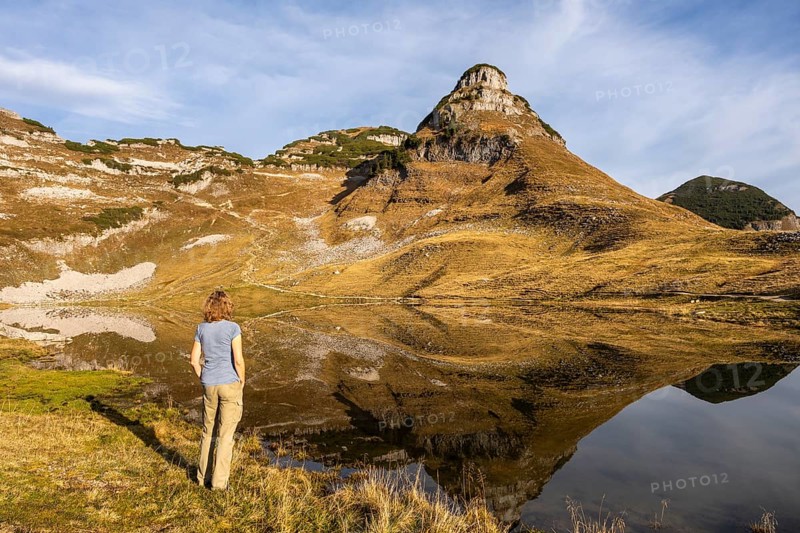 Lake Augstsee and the Atterkogel mountain on the Loser. A hiker stands on the shore. Autumn, good weather, blue sky. Reflection. Altaussee, Bad Aussee, Ausseer Land, Totes Gebirge, Styria, Upper Austria, Austria, Europe