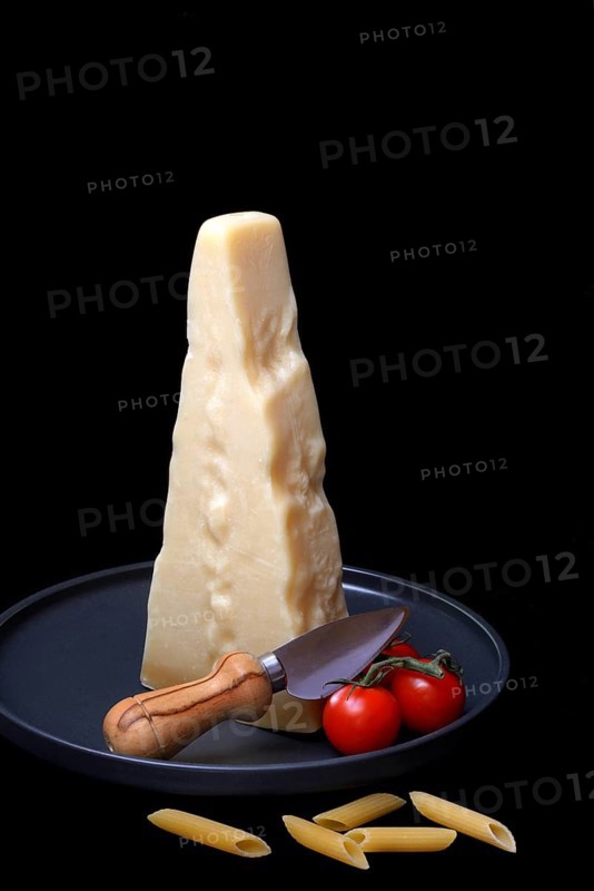 A piece of Parmesan cheese with cheese knife, pasta and tomatoes, Italy, Europe