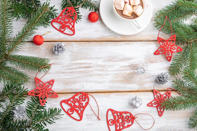 Christmas or New Year frame composition. Decorations, red stars, bells, cones, fir and spruce branches, cup of coffee, on a white wooden background. Top view, copy space, flat lay
