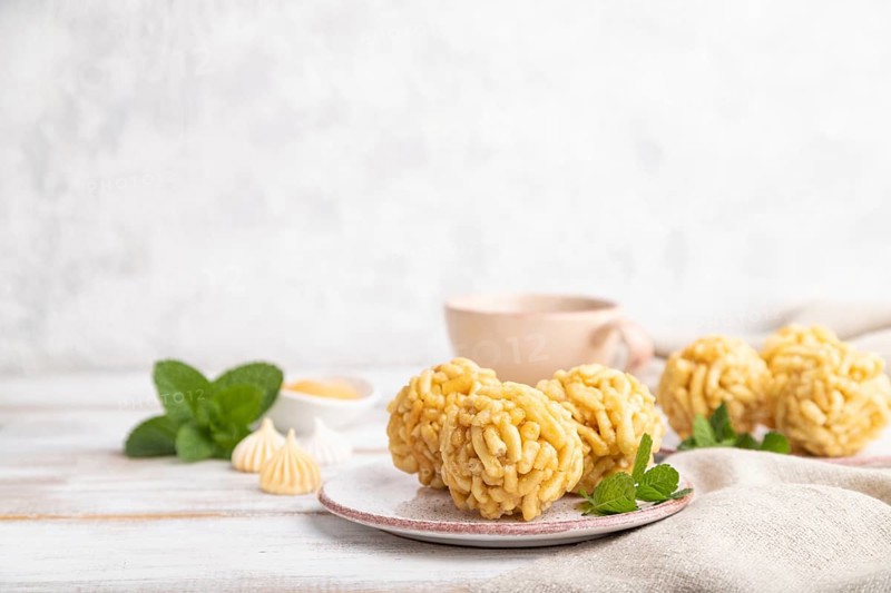 Traditional Tatar candy chak-chak made of dough and honey with cup of coffee on a white wooden background and linen textile. Side view, copy space, selective focus